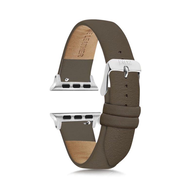 Pode incluir: Uma pulseira de rel&oacute;gio em couro cor de taupe com uma fivela de metal prateado e ferragens de fixa&ccedil;&atilde;o prateadas. O interior da pulseira est&aacute; gravado com o texto GENUINE LEATHER e a fivela tem gravadas as letras BZ.