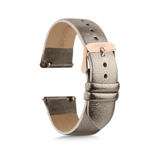 May include: A metallic champagne-colored watch strap with a textured leather surface and a rose gold-toned metal buckle. The strap features two leather loops, a series of adjustment holes, and quick-release spring bars at the attachment ends.