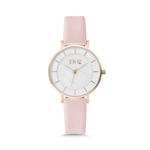 May include: A rose gold watch with a white face and a pink leather band. The watch face has a mother-of-pearl effect and the brand name "1302" is printed on the face.