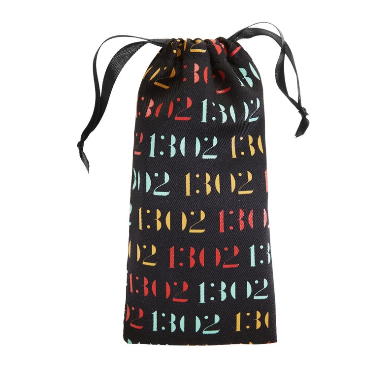 May include: A black drawstring pouch featuring a repeating pattern of the text 1302 printed in alternating colors of red, yellow, and light blue. The bag is made of fabric and includes black ribbon drawstrings at the top for closure.
