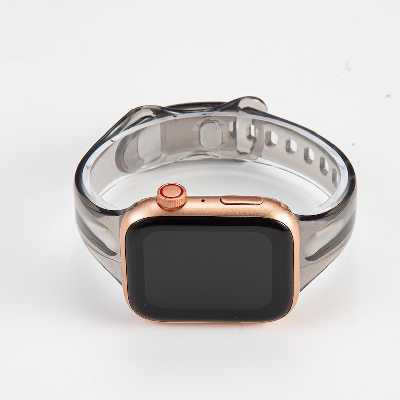 K&ouml;nnte beinhalten: Eine Apple Watch in Ros&eacute;gold mit einem durchsichtigen, transparenten Silikonarmband. Das Zifferblatt der Uhr ist schwarz und das Armband hat ein strukturiertes Design.