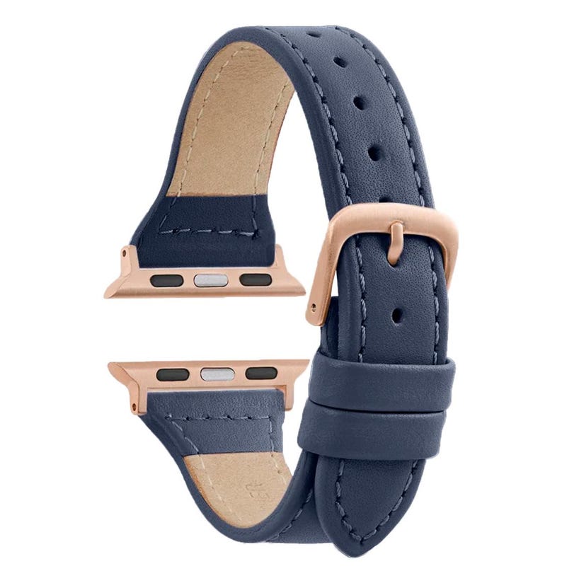 May include: A dark blue leather watch band with rose gold hardware and stitching. The band is designed for Apple Watch.
