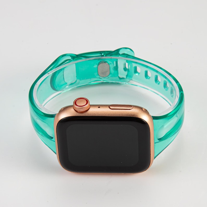 K&ouml;nnte beinhalten: Eine ros&eacute;goldene Apple Watch mit einem durchsichtigen t&uuml;rkisfarbenen Silikonarmband. Das Zifferblatt der Uhr ist schwarz und das Armband hat einen Schlie&szlig;enverschluss.