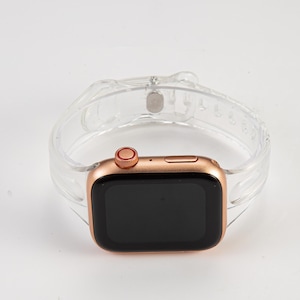 K&ouml;nnte beinhalten: Eine Apple Watch in Ros&eacute;gold mit einem klaren, strukturierten Silikonarmband. Das Zifferblatt der Uhr ist schwarz und das Armband hat einen Schlie&szlig;enverschluss.