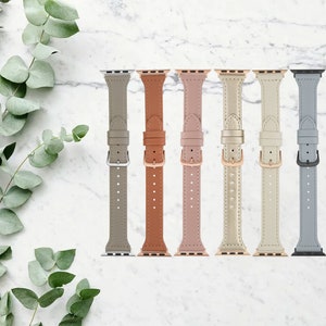 May include: Seven different colored leather watch bands for an Apple Watch. The bands are in the colors gray, brown, pink, gold, white, and blue.