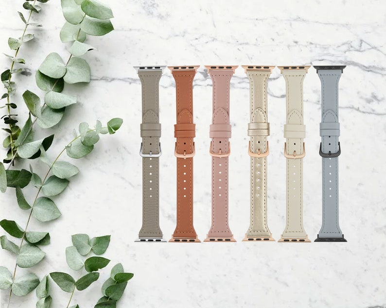 May include: Seven different colored leather watch bands for an Apple Watch. The bands are in the colors gray, brown, pink, gold, white, and blue.