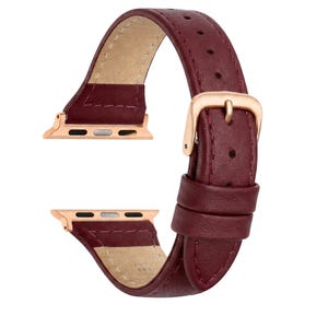 May include: A burgundy leather watch strap with a gold-coloured buckle and connectors. The strap is made of smooth, high-quality leather and features a classic design. The watch strap is designed to fit a smartwatch.