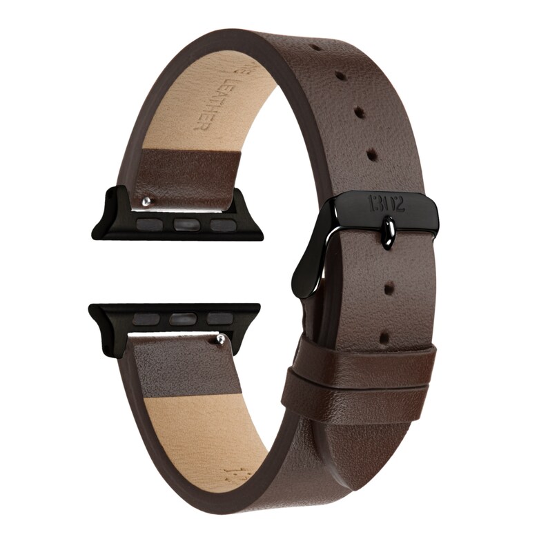 以下が含まれることがあります： 黒いバックルと黒い金属アダプターが付いた、茶色の革製のApple Watchバンド。バンドは本革製で、質感のある仕上げになっています。