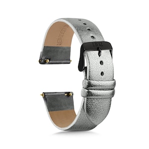 May include: A metallic silver watch strap with a textured finish and a black buckle. The strap features two loops, a series of adjustment holes, and gold-toned spring bars at the ends. The interior is lined with a tan material marked with the text LEATHER.