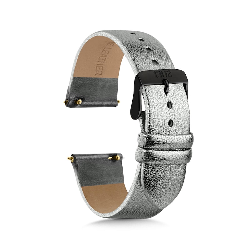 May include: A metallic silver watch strap with a textured finish and a black buckle. The strap features two loops, a series of adjustment holes, and gold-toned spring bars at the ends. The interior is lined with a tan material marked with the text LEATHER.
