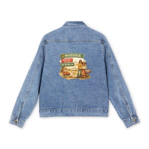 May include: A light blue denim jacket featuring a graphic on the back with road signs reading WOODSTOCK, WRONG EXIT, and TRY BETHEL. The illustration depicts two figures standing near a small orange car on a road with the text BETHEL 1969.