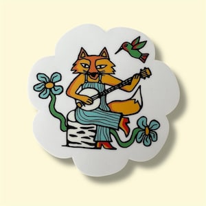 May include: A white, flower-shaped decorative item featuring a cartoon fox playing a banjo. The fox is orange and yellow, wearing blue overalls. A green hummingbird and blue flowers accent the design. The item has a whimsical, folk art style.
