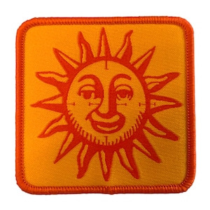 Puede incluir: Parche bordado naranja con una cara de sol sonriente sobre un fondo amarillo.