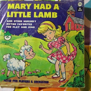 May include: A vintage record featuring the nursery rhyme "Mary Had A Little Lamb" with illustrations of a girl and a lamb. The record is titled "Mary Had A Little Lamb and Other Nursery Rhyme Favorites for Play and Sing".