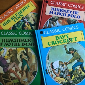 May include: Four classic comic books with colorful covers. The titles are "Huckleberry Finn", "Journey of Marco Polo", "Hunchback of Notre Dame", and "Davy Crockett".