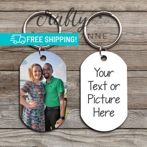 May include: Two oval-shaped keychains. One keychain features a photo of a couple, a woman in a floral dress and a man in a green shirt. The other keychain is white with the text "Your Text or Picture Here".