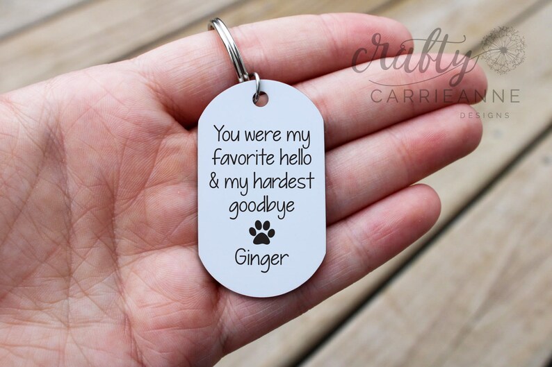 May include: White metal keychain with a paw print and the text "You were my favourite hello & my hardest goodbye Ginger".
