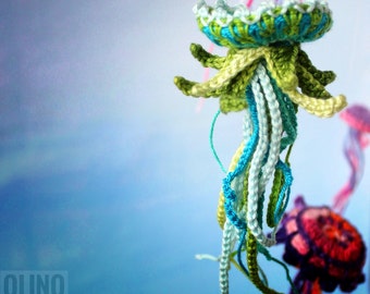 May include: A crocheted jellyfish with a green and white bell and long blue, green, and white tentacles.