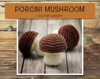 Op de afbeelding: Drie gehaakte bruine en witte eekhoorntjesbrood paddenstoelen op een houten oppervlak. De afbeelding bevat de tekst "PORCINI MUSHROOM crochet pattern".