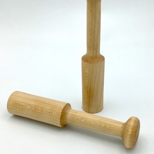 May include: Two wooden mallets with rounded ends. The mallets are made of light brown wood and have a smooth finish.