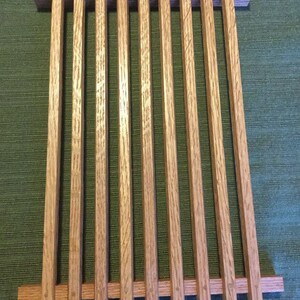 Puede incluir: Una rejilla de enfriamiento rectangular de madera con un acabado de madera natural. La rejilla est&aacute; hecha de listones de madera delgados, verticales, que est&aacute;n espaciados uniformemente. La rejilla es ideal para enfriar productos horneados u otros alimentos.