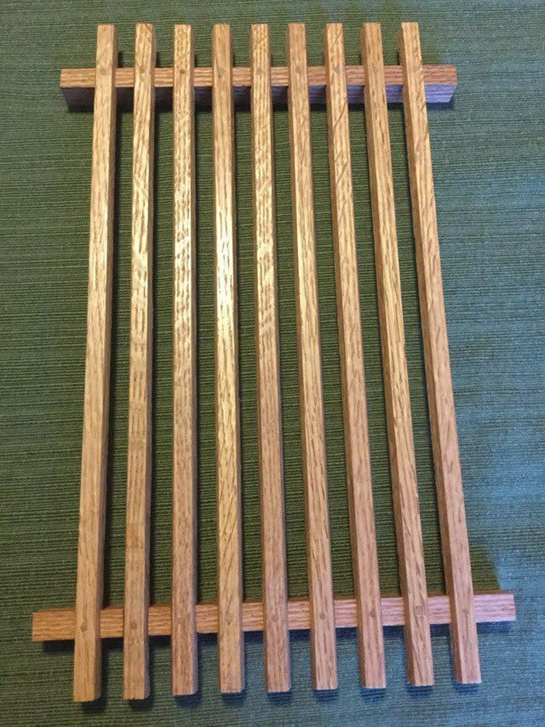 Puede incluir: Una rejilla de enfriamiento rectangular de madera con un acabado de madera natural. La rejilla est&aacute; hecha de listones de madera delgados, verticales, que est&aacute;n espaciados uniformemente. La rejilla es ideal para enfriar productos horneados u otros alimentos.