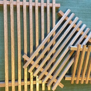 Puede incluir: Tres bandejas de madera con listones de diferentes tama&ntilde;os, apiladas una encima de la otra. Las bandejas son de madera natural de color marr&oacute;n claro.