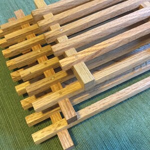 Puede incluir: Marcos de madera apilados con un patr&oacute;n de rejilla, hechos de madera marr&oacute;n claro. Los marcos est&aacute;n dispuestos en un patr&oacute;n escalonado, creando una textura visual.
