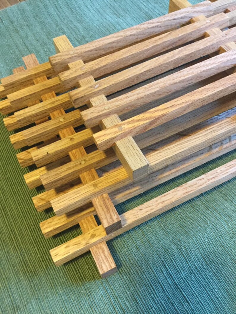 Puede incluir: Marcos de madera apilados con un patr&oacute;n de rejilla, hechos de madera marr&oacute;n claro. Los marcos est&aacute;n dispuestos en un patr&oacute;n escalonado, creando una textura visual.