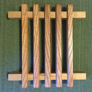 Puede incluir: Un estante de madera con cinco listones verticales y dos listones horizontales. El estante est&aacute; hecho de madera marr&oacute;n claro con un acabado natural.