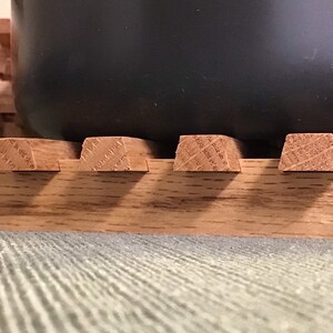 Puede incluir: Un posavasos de madera con una olla gris oscuro encima. El posavasos est&aacute; hecho de varias piezas de madera unidas.