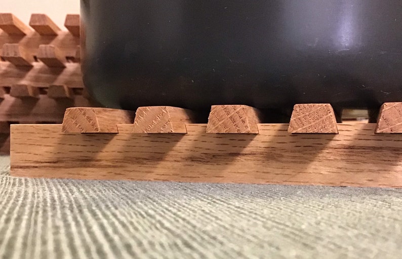 Puede incluir: Un posavasos de madera con una olla gris oscuro encima. El posavasos est&aacute; hecho de varias piezas de madera unidas.