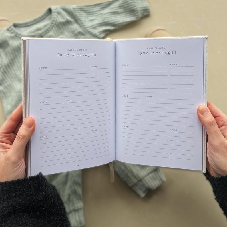 K&ouml;nnte beinhalten: Ein offenes wei&szlig;es Tagebuch mit dem Titel "Baby is here! Love messages" auf dem Vorder- und Hinterdeckel. Das Tagebuch hat linierte Seiten zum Schreiben von Nachrichten.