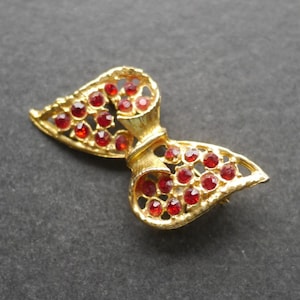 Gold tone bow brooch with red rhinestones