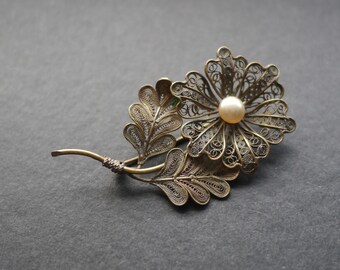 Silver tone filigree flower brooch with faux pearl bead