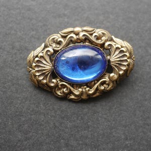Vintage gold tone brooch with blue glass cabochon