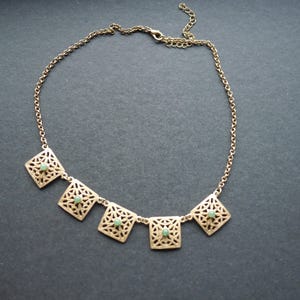 Gliederkette aus goldfarbenem Metall mit kleinen grünen Halbedelsteinen