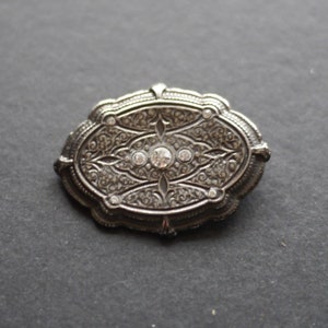 Ornate silver tone metal vintage brooch with clear rhinestones image 1