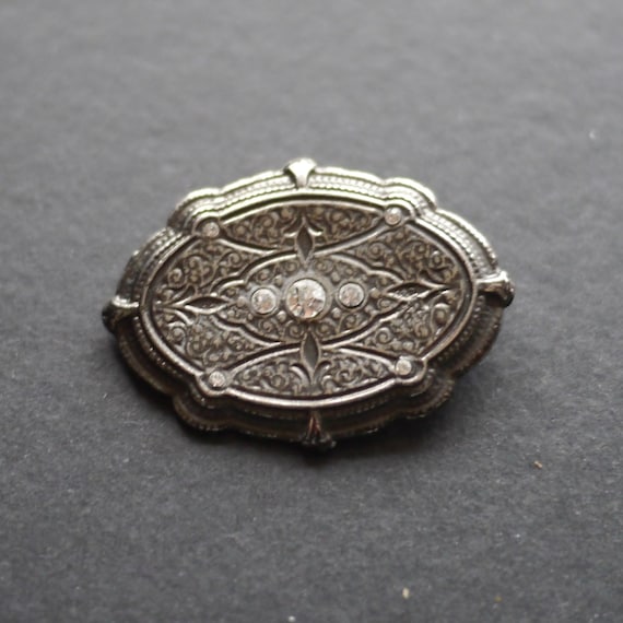 Ornate silver tone metal vintage brooch with clea… - image 1