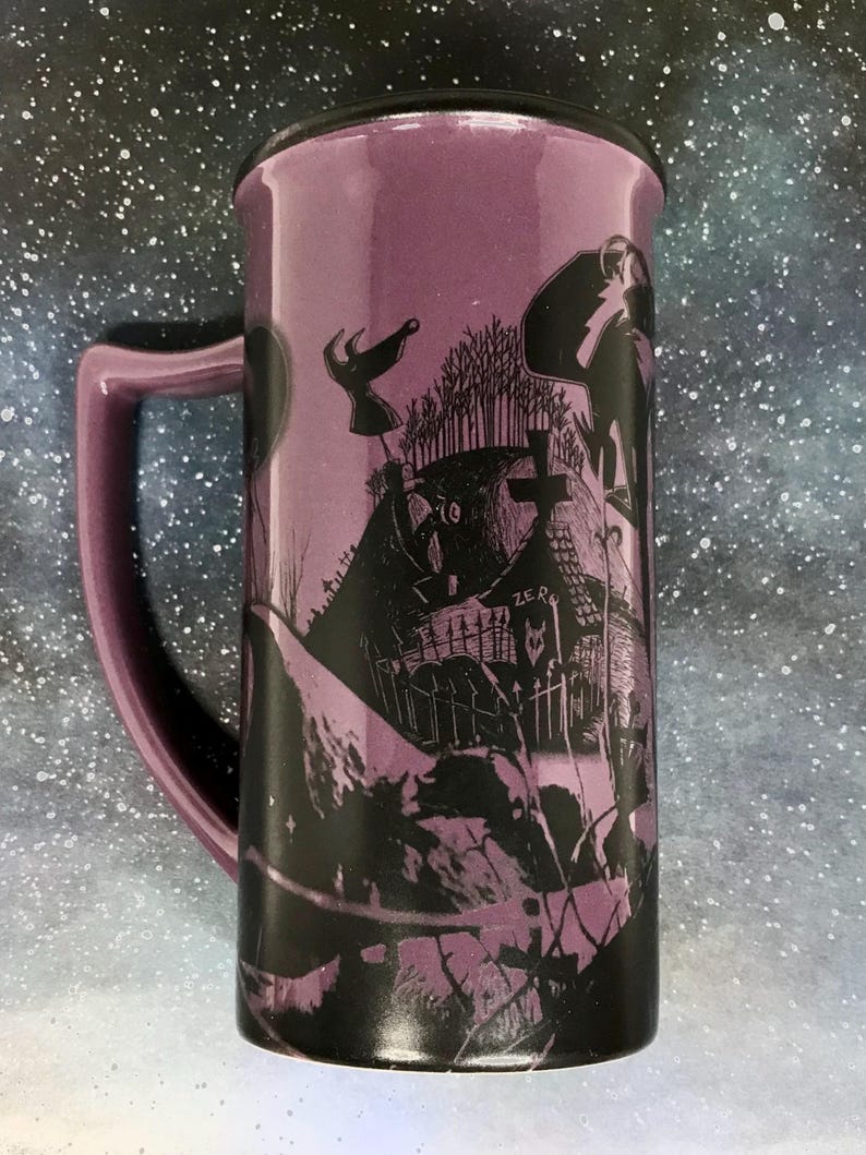 May include: Purple ceramic travel mug with a black lid and handle. The mug features a black graphic design of a spooky graveyard scene with characters. The mug is tall and cylindrical, perfect for hot or cold beverages.