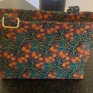 A rectangular tote bag featuring a floral design in teal, orange, and purple. The bag has two handles with gold-coloured metal hardware. The interior lining is a solid orange colour. The bag was made using the Phillippa Crossbody sewing pattern.