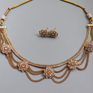 May include: A gold necklace with multiple strands and clear crystal flower accents. Matching earrings with clear crystal flower accents are included.