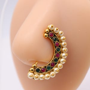 May include: Gold nose ring with a half-circle design, featuring a row of green and pink gemstones and a border of white pearls.