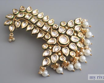 Könnte beinhalten: Ein goldfarbenes, verziertes Haaraccessoire mit klaren, tropfenförmigen und quadratischen Edelsteinen. Das Stück ist mit kleinen, hängenden Perlenclustern verziert und hat ein zartes, geschwungenes Design. Der Hintergrund ist einfarbig hellgrau.