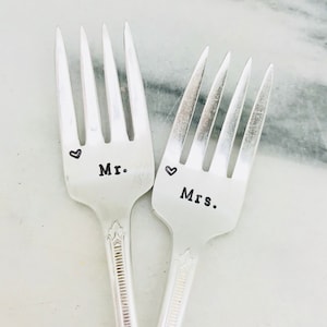 May include: Two silver forks with the words "Mr." and "Mrs." engraved on them. Each fork has a small heart symbol next to the word.