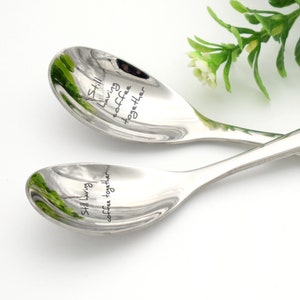 May include: Two silver spoons with the inscription "Still having coffee together" on each spoon.