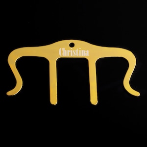 Puede incluir: Pinza para el pelo de metal de color dorado con el nombre "Christina" grabado.