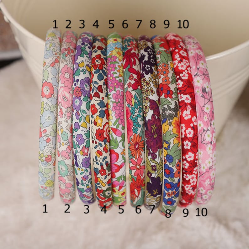 K&ouml;nnte beinhalten: Zehn mit Stoff bezogene Haarb&auml;nder mit floralen Mustern, nummeriert von 1 bis 10. Die Haarb&auml;nder zeigen verschiedene Blumenmuster und Farben, ideal f&uuml;r verschiedene Outfits.