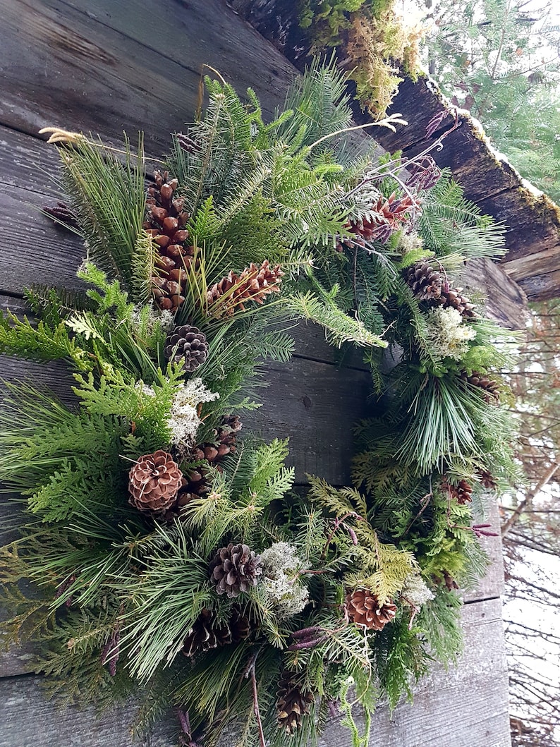 K&ouml;nnte beinhalten: Ein gr&uuml;ner, brauner und wei&szlig;er Weihnachtskranz aus Kiefern&auml;sten, Zapfen und anderen nat&uuml;rlichen Elementen.