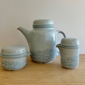 May include: A set of three blue and white ceramic kitchenware items. A teapot, a creamer, and a sugar bowl with a lid. All three items have a floral pattern.